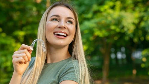 Woman standing outside holding clear aligner