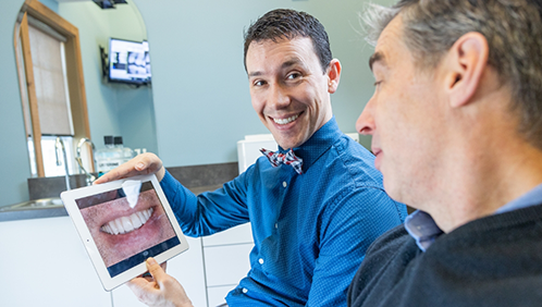 Doctor Parry showing a patient a close up photo of their teeth