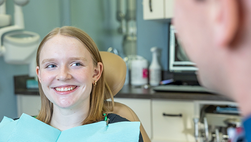 Teenage girl in the dental chair smiling at her dentist