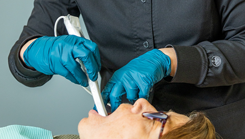 Dental team member taking digital scans of a patient's teeth