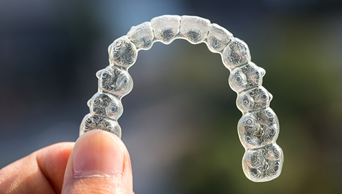 Hand holding a clear aligner