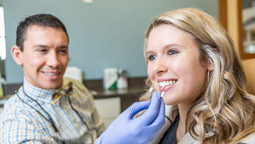 Doctor Parry holding veneers in front of a patient's teeth
