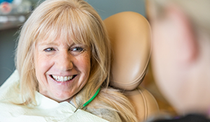 Woman in the dental chair grinning at her dentist
