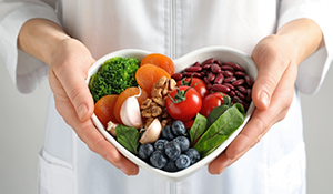 Person holding a heart shaped bowl of salad
