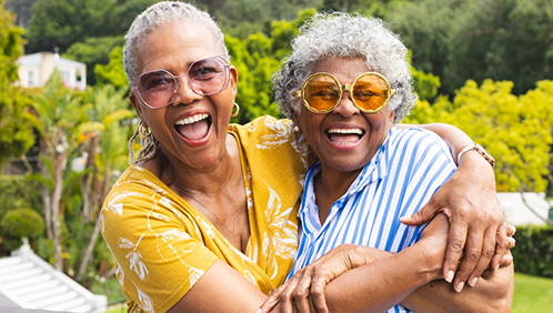 Two older women laughing together outdoors