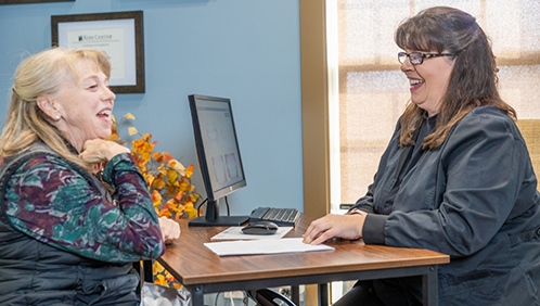 Woman sitting across a desk from a dental team member