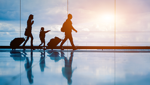 Family of three carrying luggage through an airport