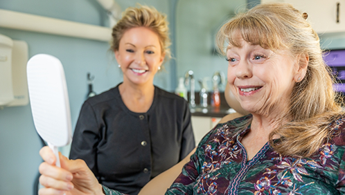 Woman in the dental chair admiring her smile in a mirror