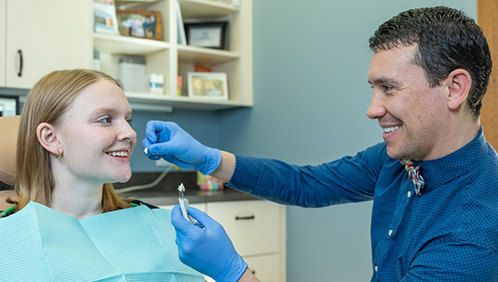 Doctor Parry holding a veneer in front of a patient's teeth