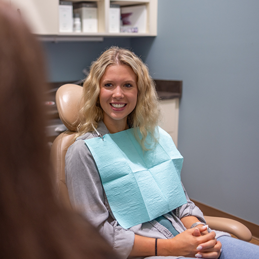 Woman in dental office smiling at dentist