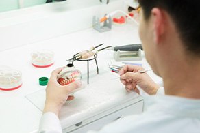 Dental laboratory technician carving a set of dentures on a cast