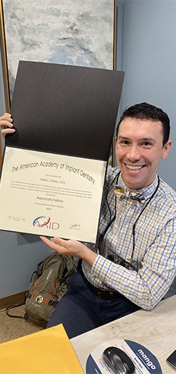 Dr. John Kois holding up educational certificate