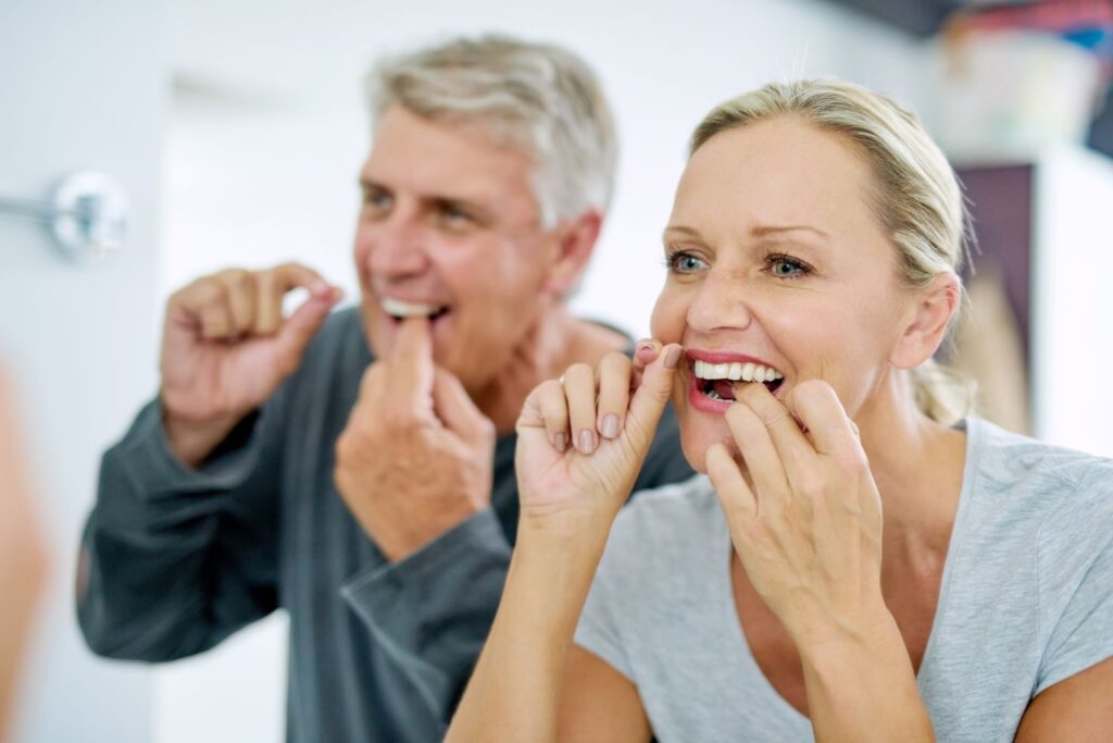 A man and woman flossing their teeth.